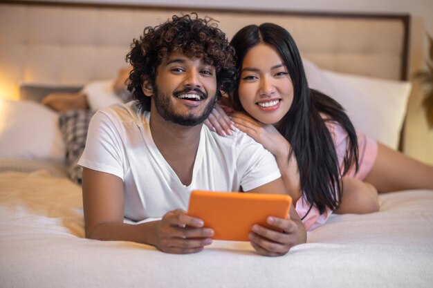 homme, à, tablette, et, étreindre, femme, coucher lit