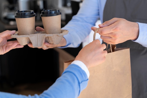 Homme avec tablier offrant des plats à emporter emballés à une cliente