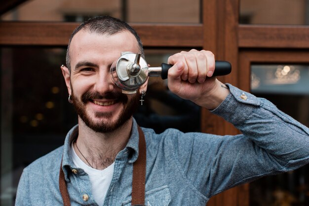 Homme en tablier posant avec composant de machine à café