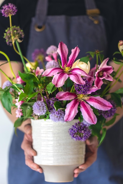 Photo gratuite un homme en tablier tient un vase de fleurs en gros plan