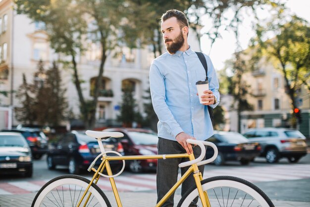 Homme avec une tasse debout près de vélo