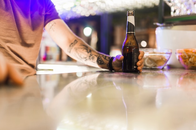 Homme tatouage, tenue, bouteille alcool, sur, table réfléchissante