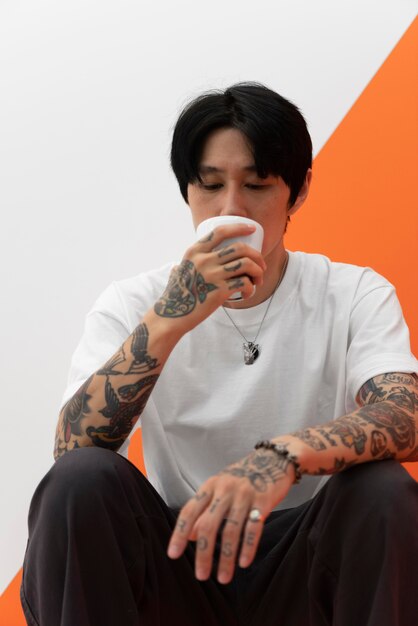 Homme avec des tatouages ayant une tasse de café au café