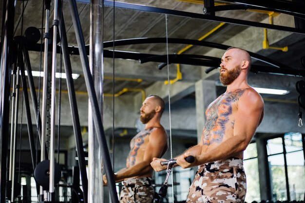 Homme tatoué faisant de l'exercice à la salle de sport