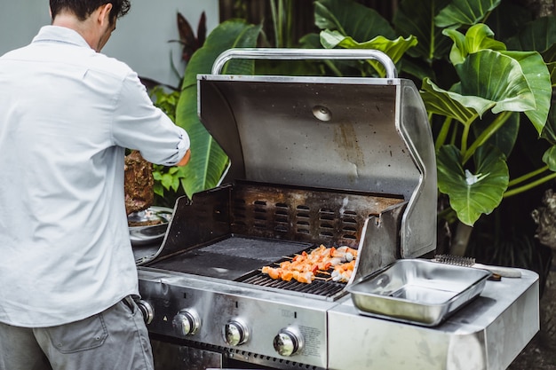 Photo gratuite un homme tatoué fait de la viande de barbecue au grand air.