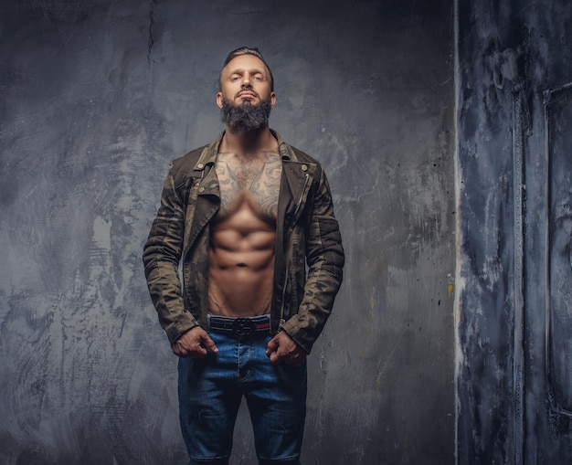 Photo gratuite homme tatoué à la mode avec barbe en jean bleu et veste sur corps nu.