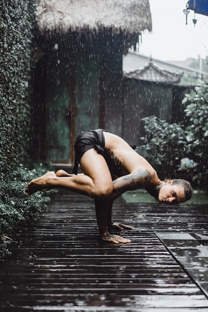 homme tatoué posant sous la pluie