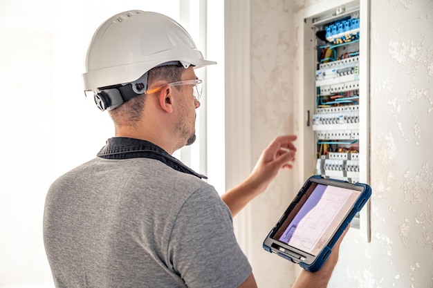 L'homme un technicien électricien travaillant dans un standard avec des fusibles utilise une tablette