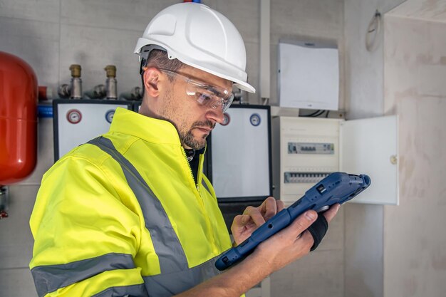 L'homme un technicien électricien travaillant dans un standard avec des fusibles utilise une tablette