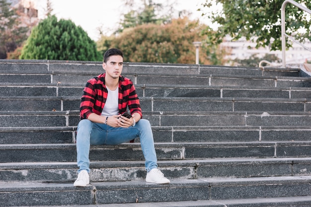 Homme avec téléphone portable assis dans l&#39;escalier