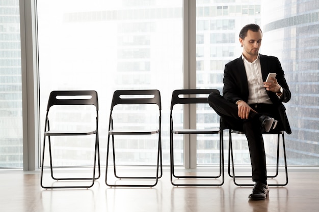 Homme avec téléphone portable en attente de son entretien