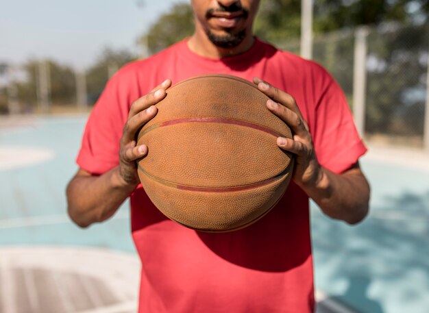 Homme tenant un ballon de basket devant lui