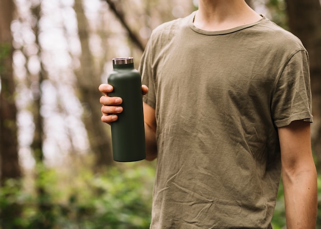 Homme tenant une bouteille d'eau dans la nature