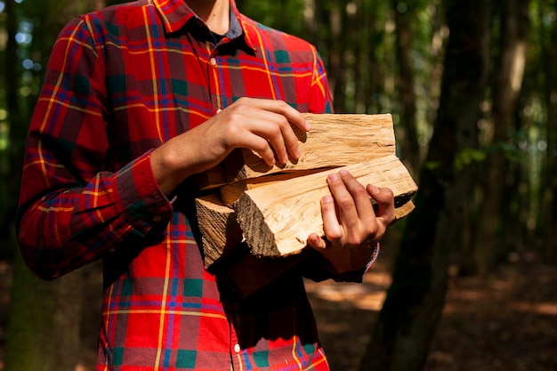 Photo gratuite homme tenant des bûches de bois pour le feu de camp