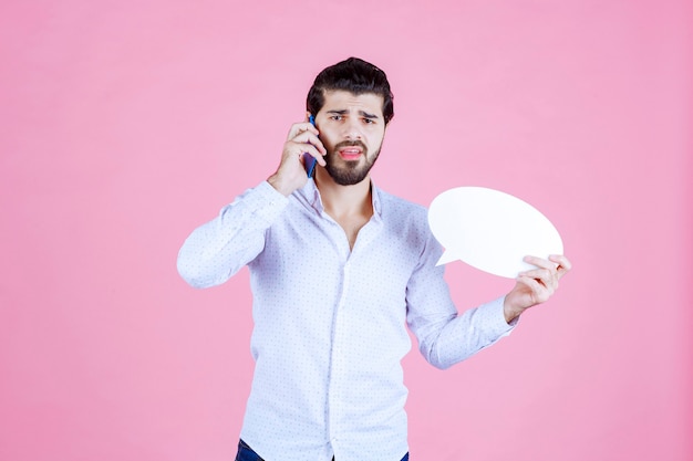 Homme tenant une bulle ovale et parlant au téléphone.