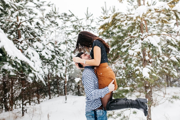 Homme tenant une femme dans les bras dans la forêt d&#39;hiver