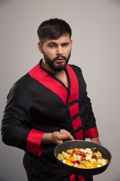 Homme tenant des légumes sur un mur gris