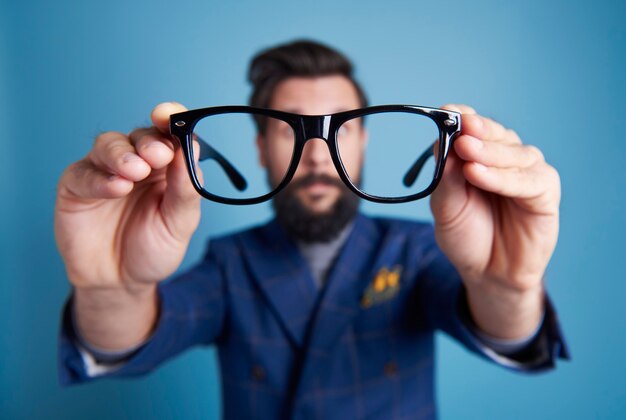 Homme tenant des lunettes devant son visage