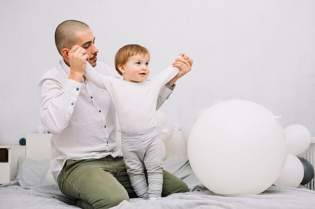 Homme tenant les mains du petit bébé sur le lit