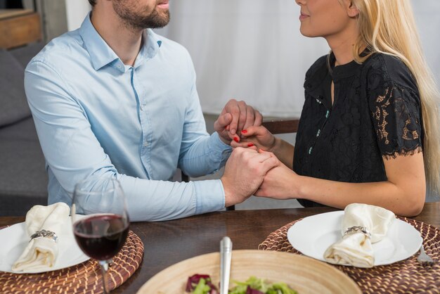 Homme tenant les mains avec une femme blonde à la table