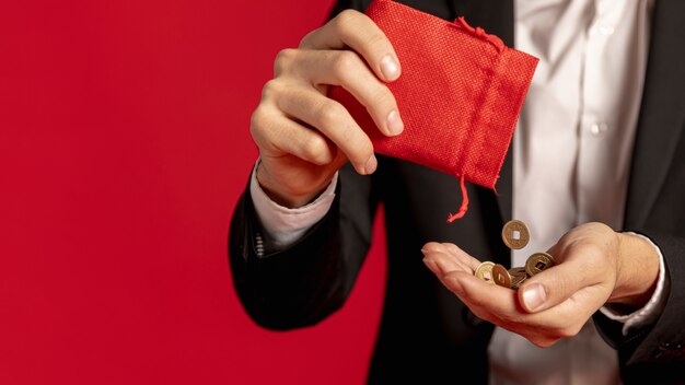 Homme tenant des pièces d'or avec un sac rouge pour le nouvel an chinois