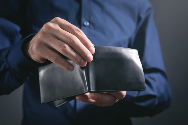 Homme tenant un portefeuille en cuir noir.