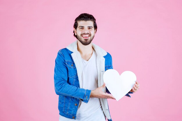 Homme tenant et présentant une figure de coeur vide avec des sourires