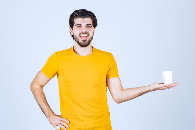 Homme tenant et promouvant une tasse de café.