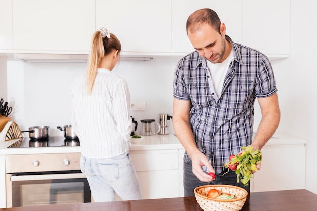 Homme tenant des radis rouges en bonne santé avec sa petite amie, debout à l&#39;arrière-plan