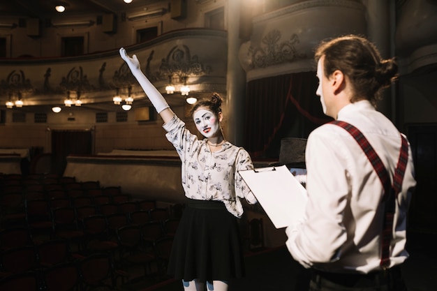 Photo gratuite homme tenant des scripts en regardant le mime féminin sur scène