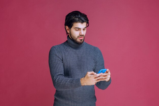 Homme tenant un smartphone, lire des messages ou envoyer des SMS.