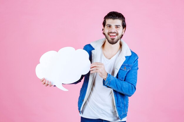 Homme tenant un tableau de réflexion vierge en forme de nuage et s'amusant