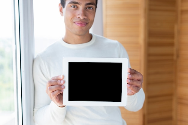 Homme tenant une tablette et face à la caméra