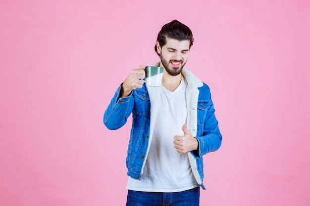 Homme tenant une tasse de boisson et se sentant satisfait