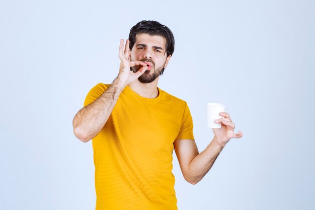 Homme tenant une tasse de café et appréciant le goût.