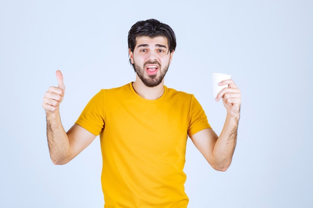 Homme tenant une tasse de café et appréciant le goût.