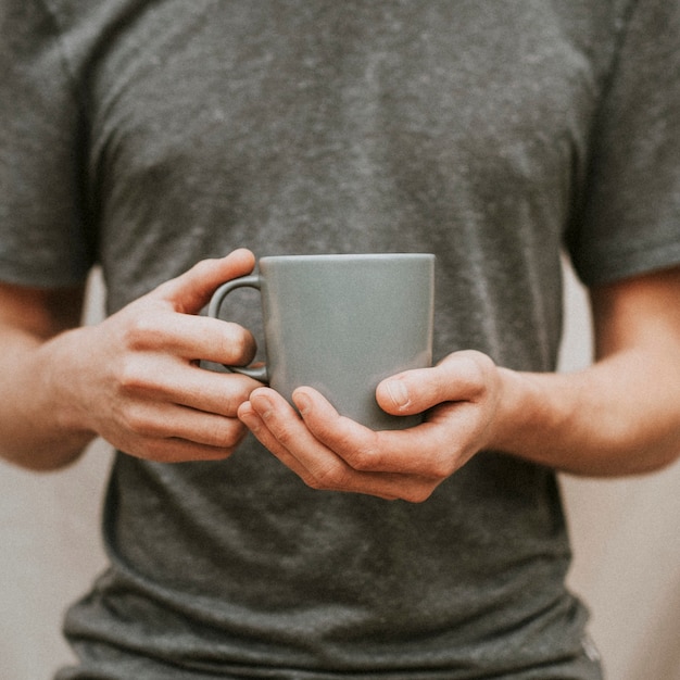 Homme tenant une tasse à café en céramique grise