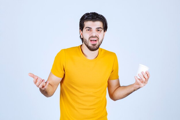 Homme tenant une tasse de café et faisant une présentation à l'aide de la main ouverte.