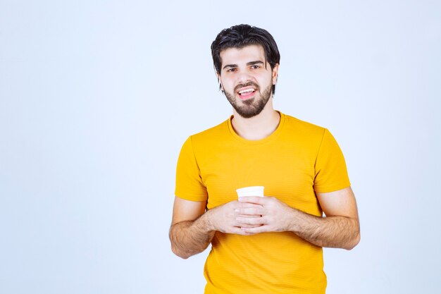 Homme tenant une tasse de café jetable entre les mains.