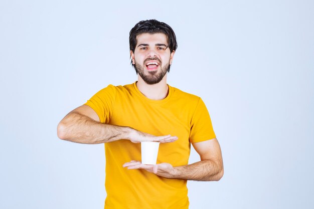 Homme tenant une tasse de café jetable entre les mains.