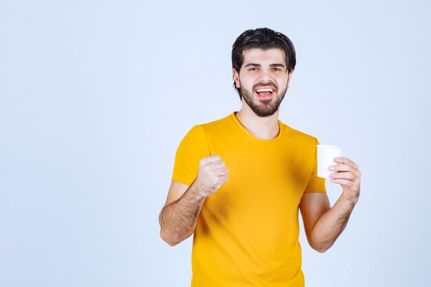 Homme tenant une tasse de café et montrant son pouvoir.