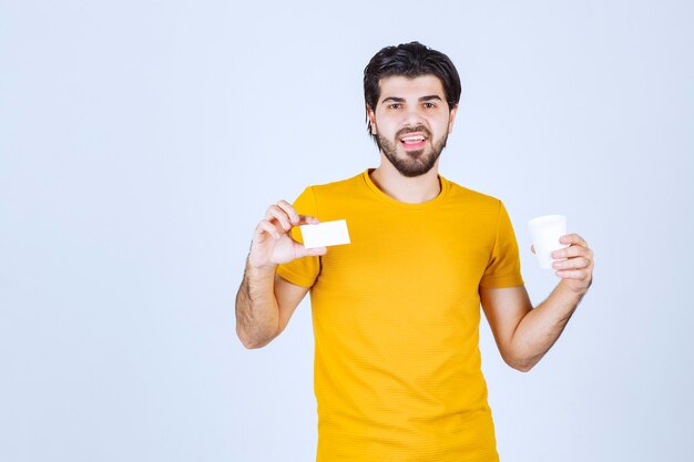 Homme tenant une tasse de café et présentant sa carte de visite.