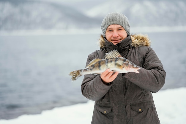 Homme tenant victorieusement le poisson qu'il a attrapé