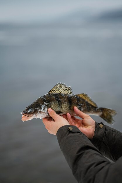 Homme tenant victorieusement le poisson qu'il a attrapé