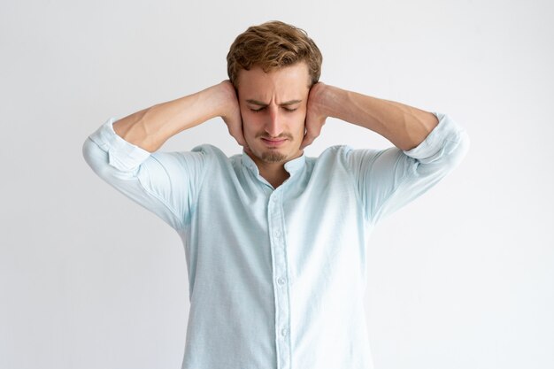 Homme tendu couvrant les oreilles avec les mains les yeux fermés