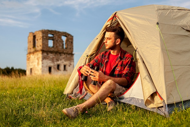 Homme en tente de camping avec jumelles