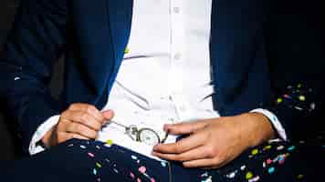 Photo gratuite homme en tenue de dîner, montre de poche entre confettis