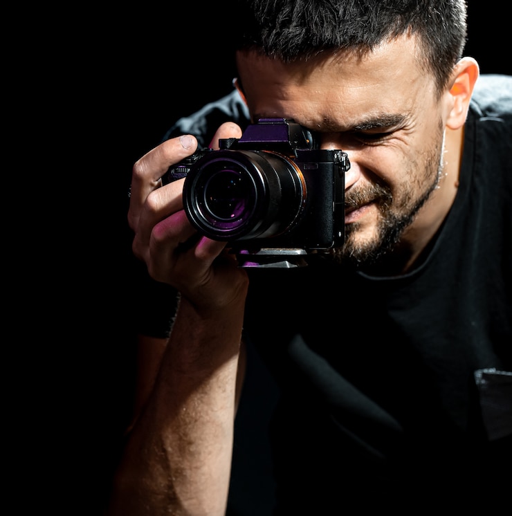 Photo gratuit l'homme tient un appareil photo et est prêt pour la prise de vue. le photographe regarde dans le viseur de l'appareil photo et prend des photos.