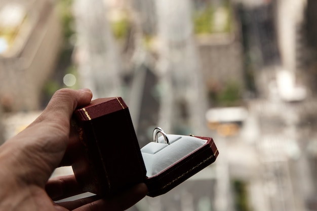 Photo gratuite homme tient une boîte rouge avec des anneaux de mariage