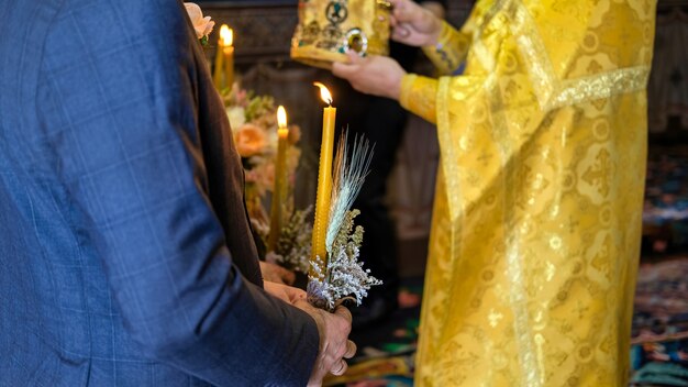 Un homme tient une bougie, prêtre orthodoxe servant dans une église. Cérémonie de mariage